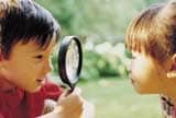 Two children looking through magnifying glass