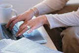 Hands using a laptop next to a cup of coffee