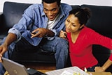 Couple sitting on couch looking at laptop