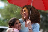 Mother and daughter smiling under umbrella