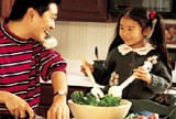 Man on phone while making dinner with daughter