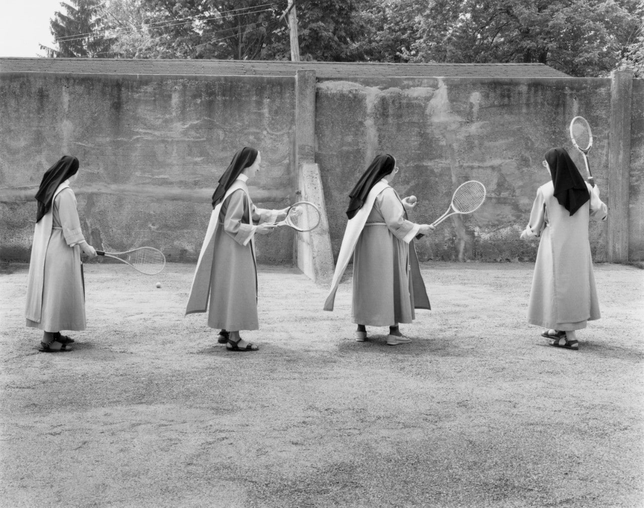 Group of nuns playing racket sport in black and white