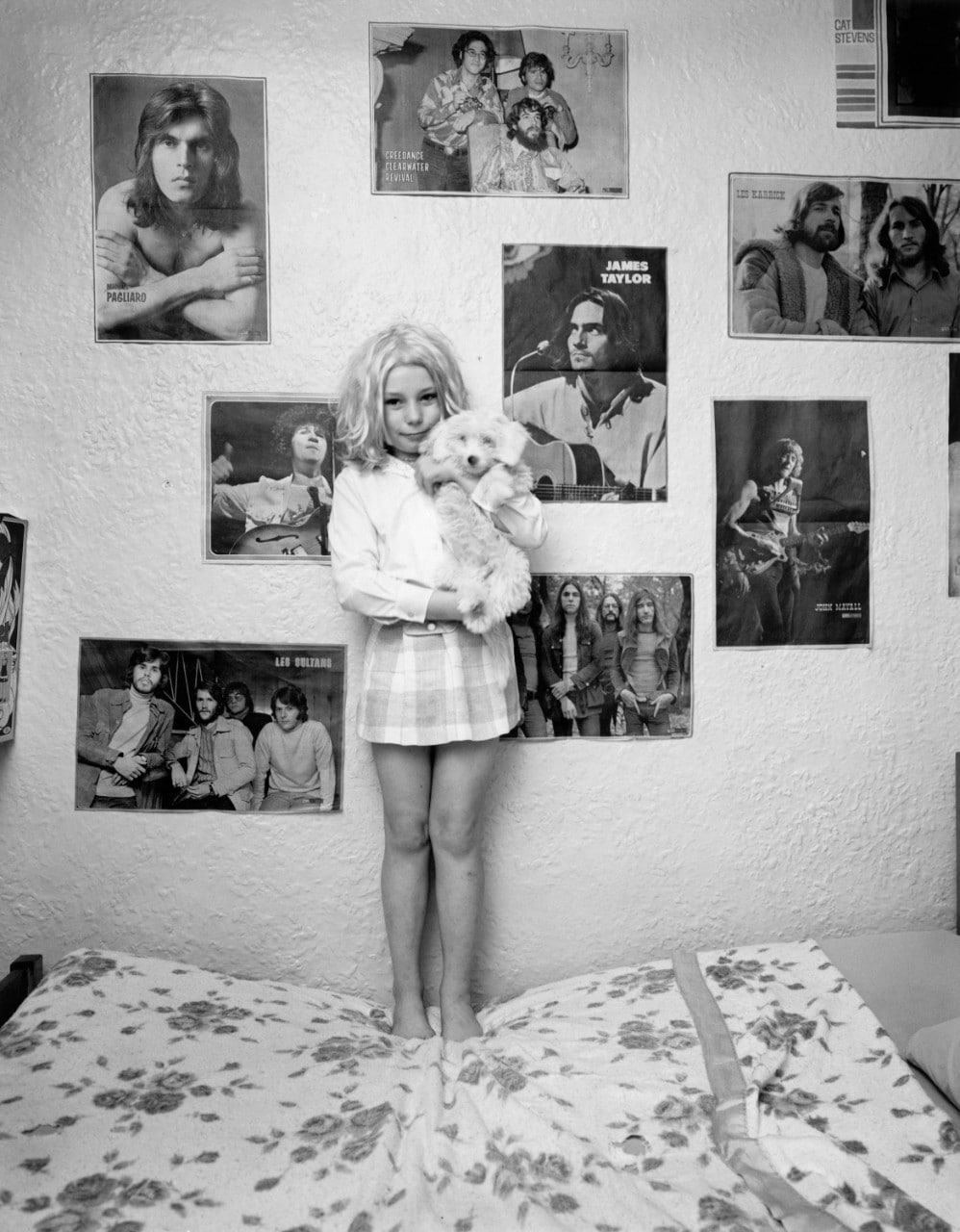 La fille se tient sur son lit tenant son chien